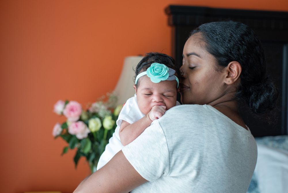 Tender moment captured against orange wall with flowers in background.