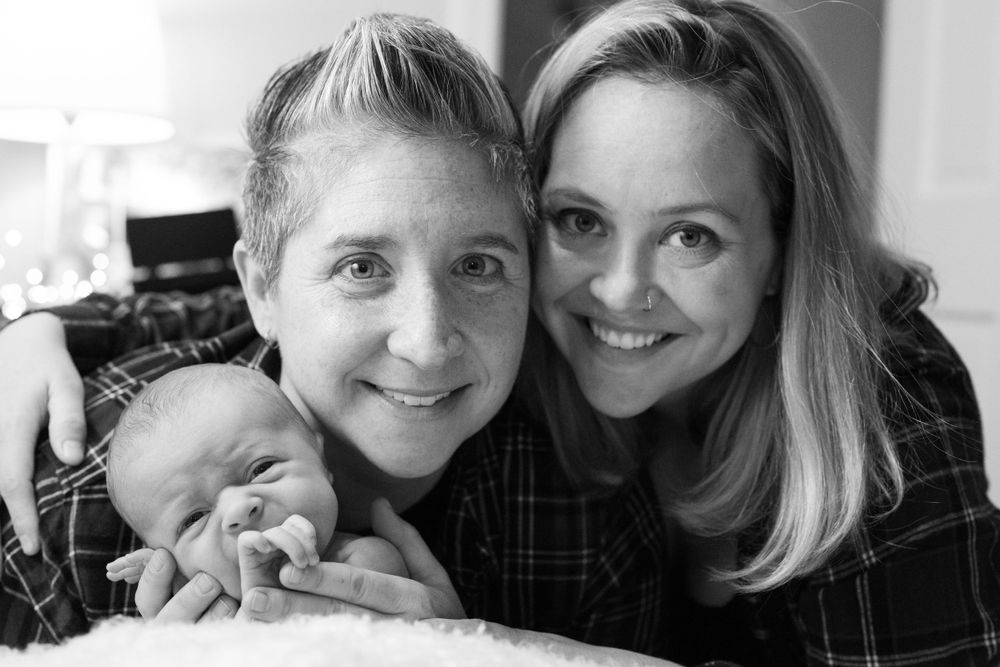 Black and white portrait of a loving family with newborn baby sharing a tender moment.