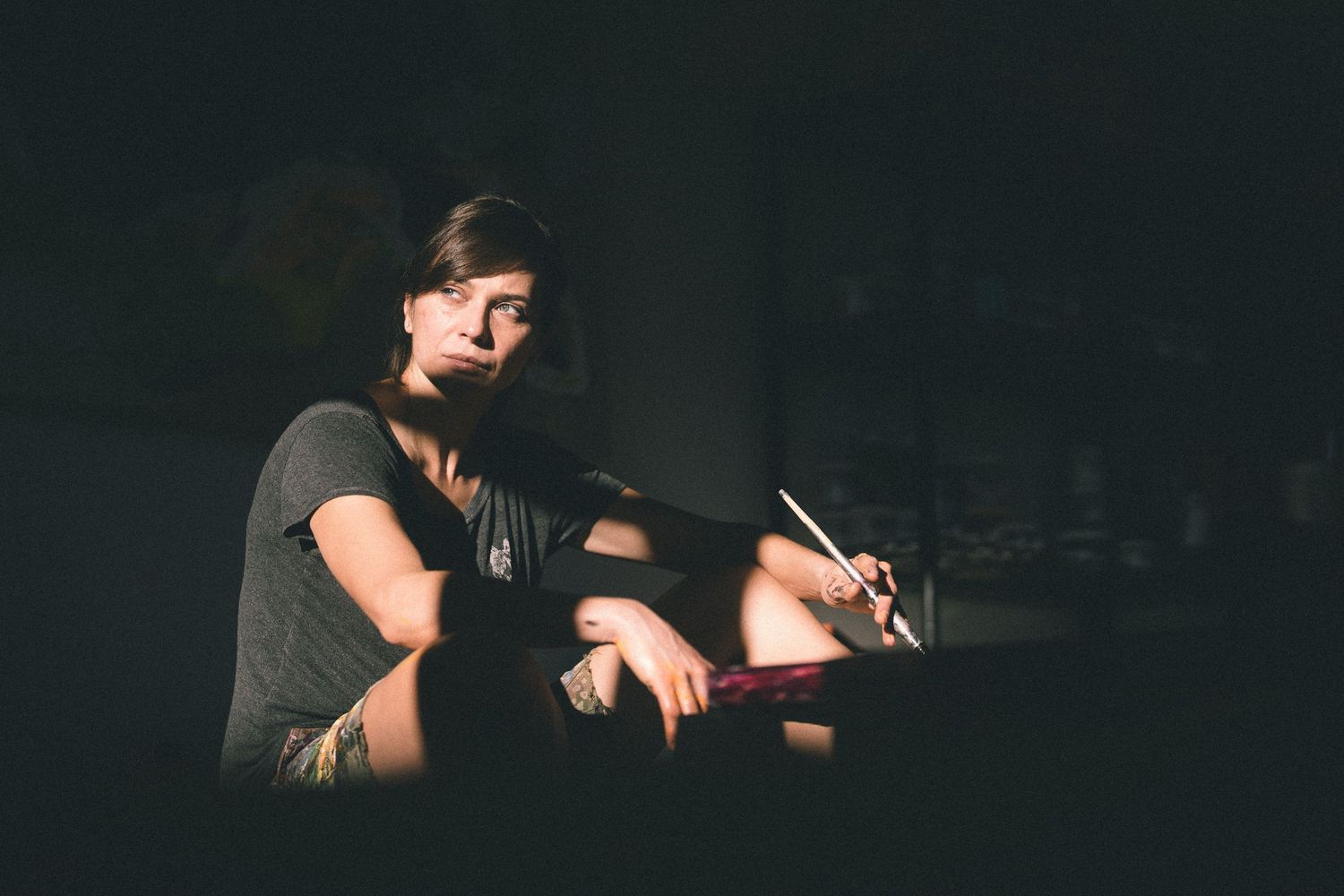 Person sitting in dark room illuminated by dramatic side lighting.
