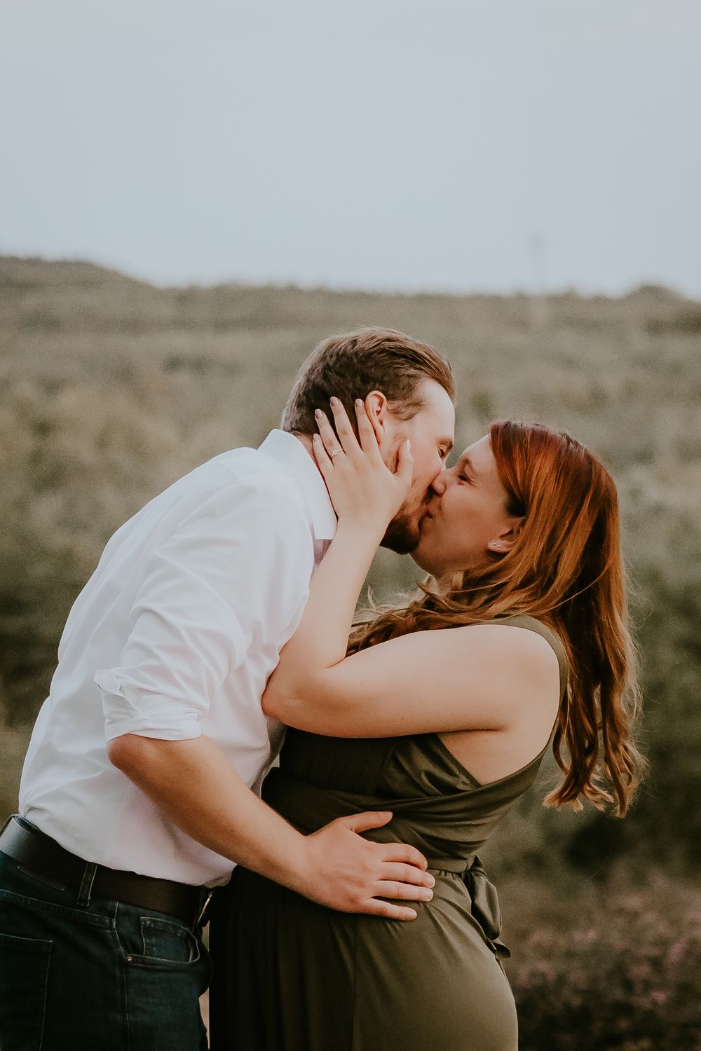 Intimate kiss between couple during sunset engagement session.