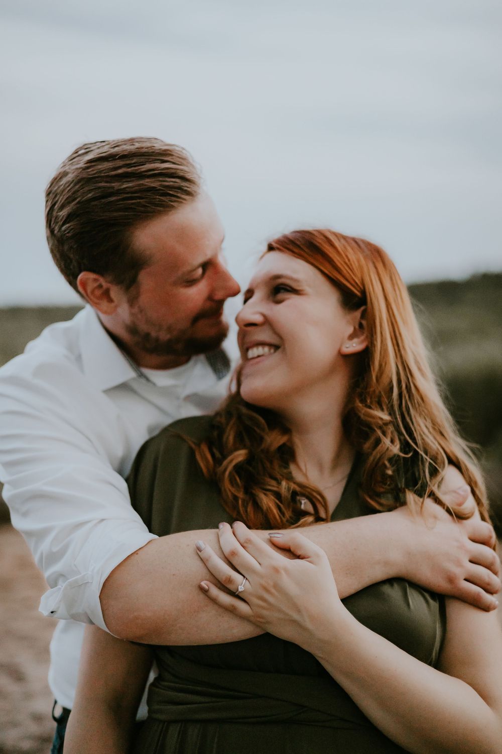 A couple shares a joyful moment together outdoors, with genuine laughter and warm embraces.