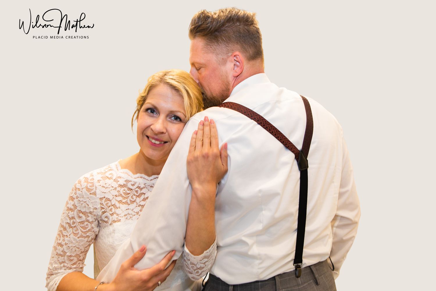 Bride focusing to camera and groom close his eyes during wedding photo session.
