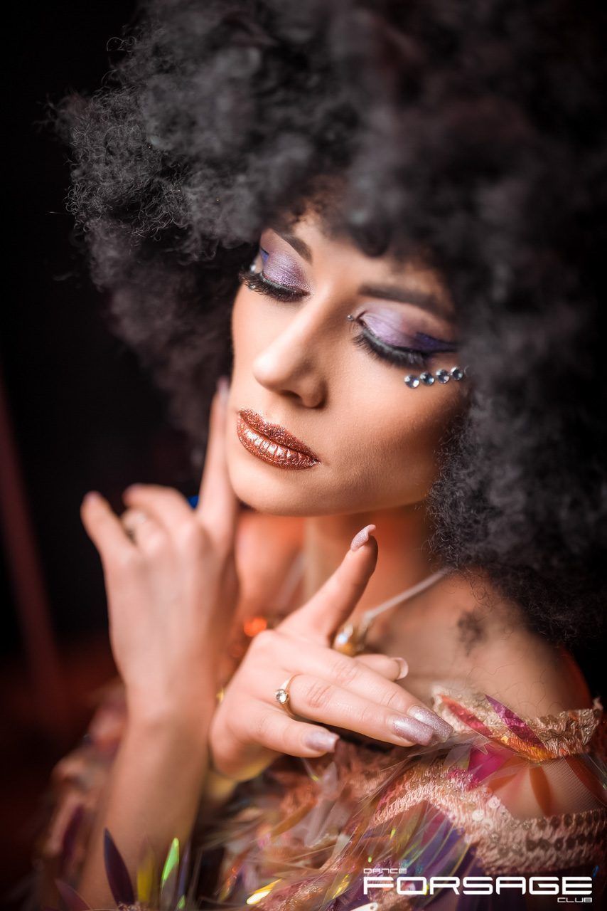 Artistic beauty portrait with glitter makeup and afro hairstyle against dark background.