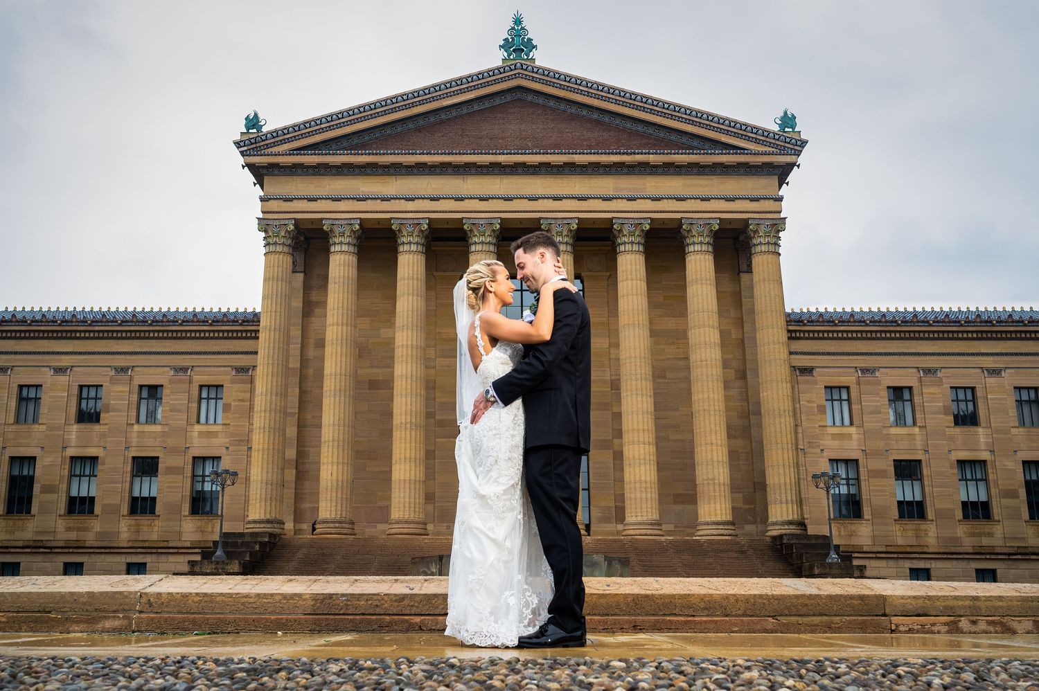 A wedding portrait with a couple embracing before the Philadelphia Museum of Art's grand columns.