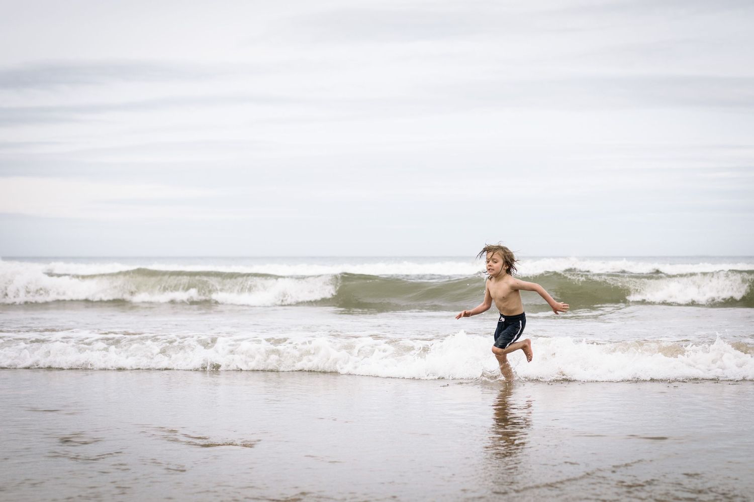 Someone runs joyfully through the ocean waves at the beach.
