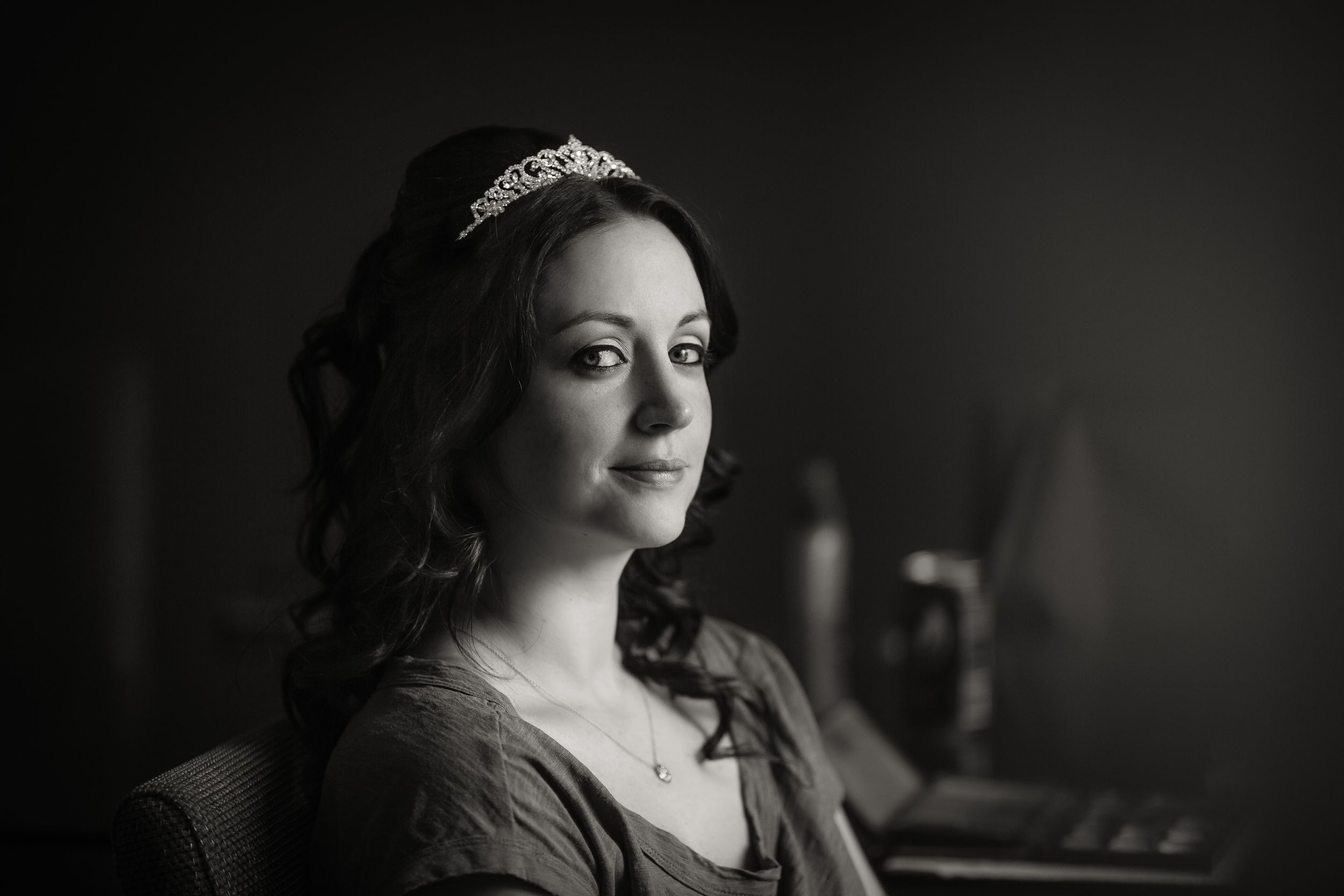 Classic black and white bridal portrait with tiara in moody lighting.