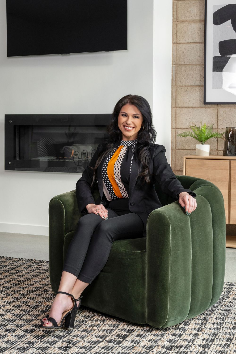 Professional seated on dark green velvet couch in contemporary office space.