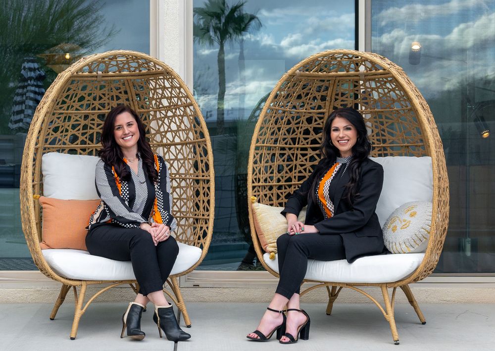 Woven rattan egg chairs arranged outdoors against modern glass building facade.