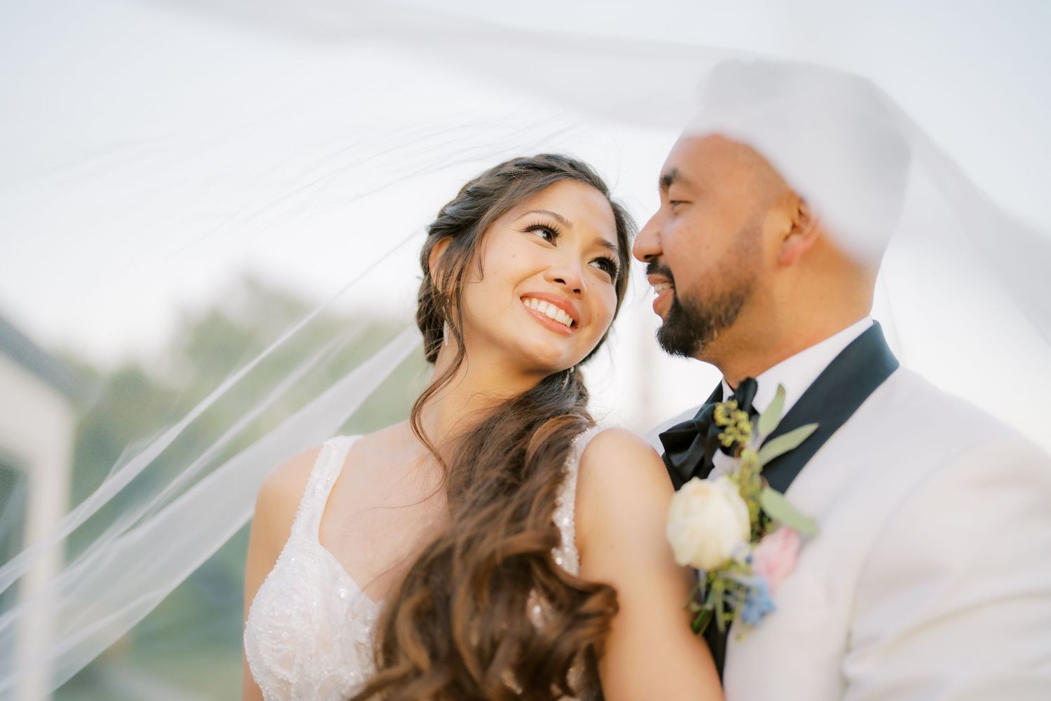 A romantic wedding moment captured under soft lighting with a flowing veil.