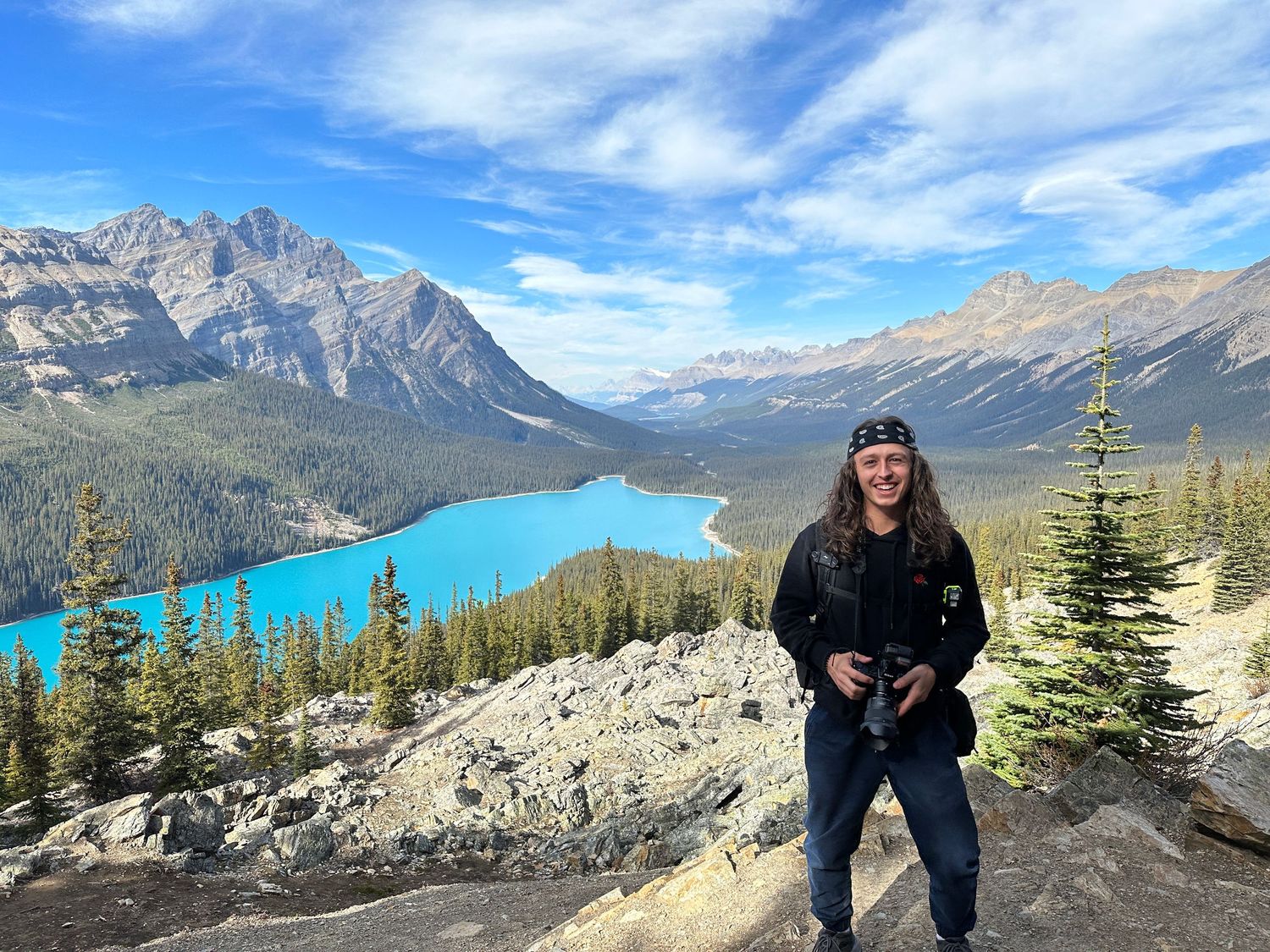 Beautiful turquoise lake surrounded by mountains in Banff National Park with hiker overlooking view.