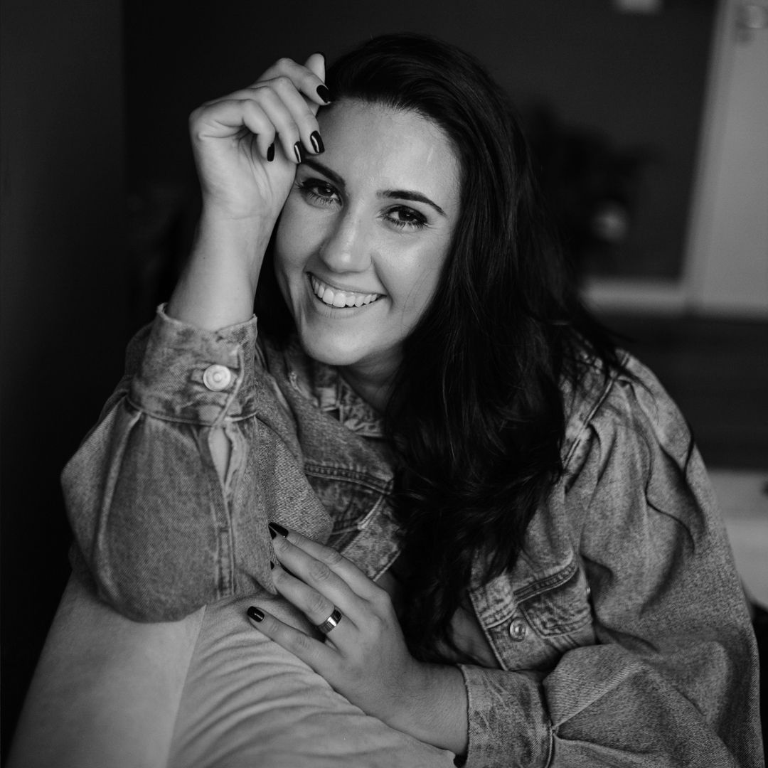 Black and white portrait of woman in vintage-style blouse with natural smile.