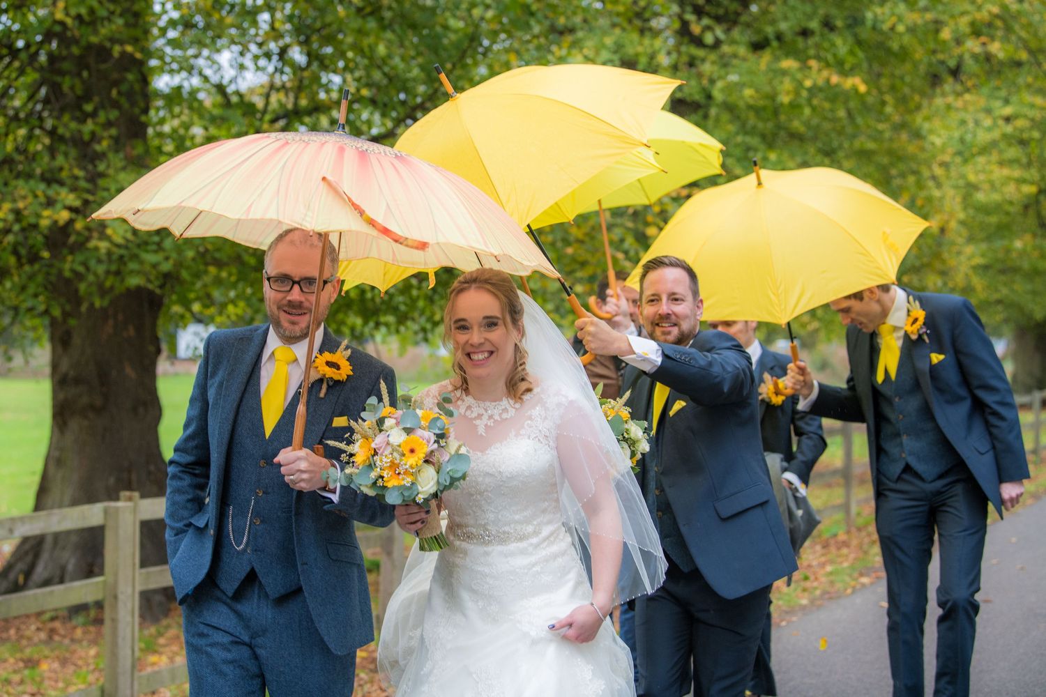 bridal party under umbrellas on a rainy wedding, at Delapre Park, Northampton