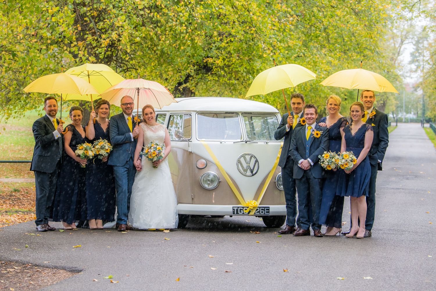 bridal party under yellow umbrella next to camper van, at Delapre Park, Northampton