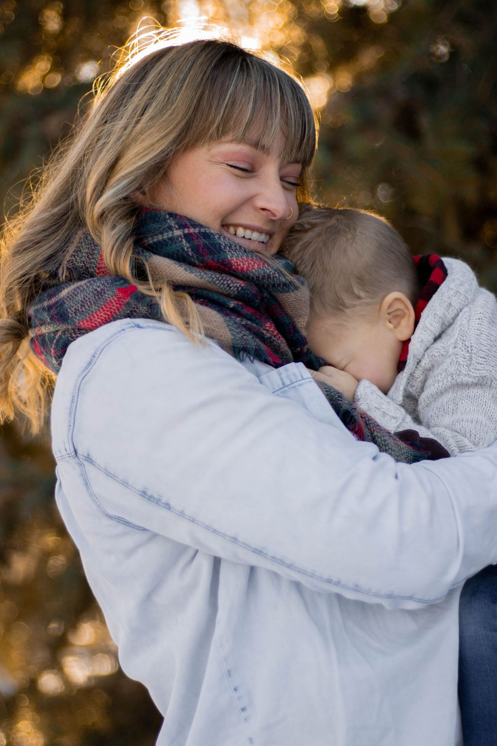 A tender parent-child moment captured in warm sunlight, showing a loving embrace while wearing winter clothing.