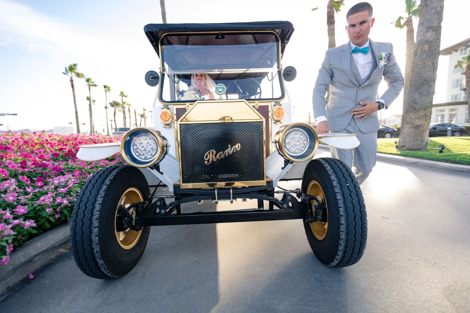 Vintage Ford Model T with gold accents parked among blooming flowers.