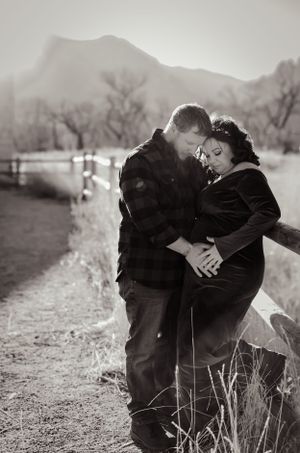 Black and white romantic portrait of couple embracing on mountain path.