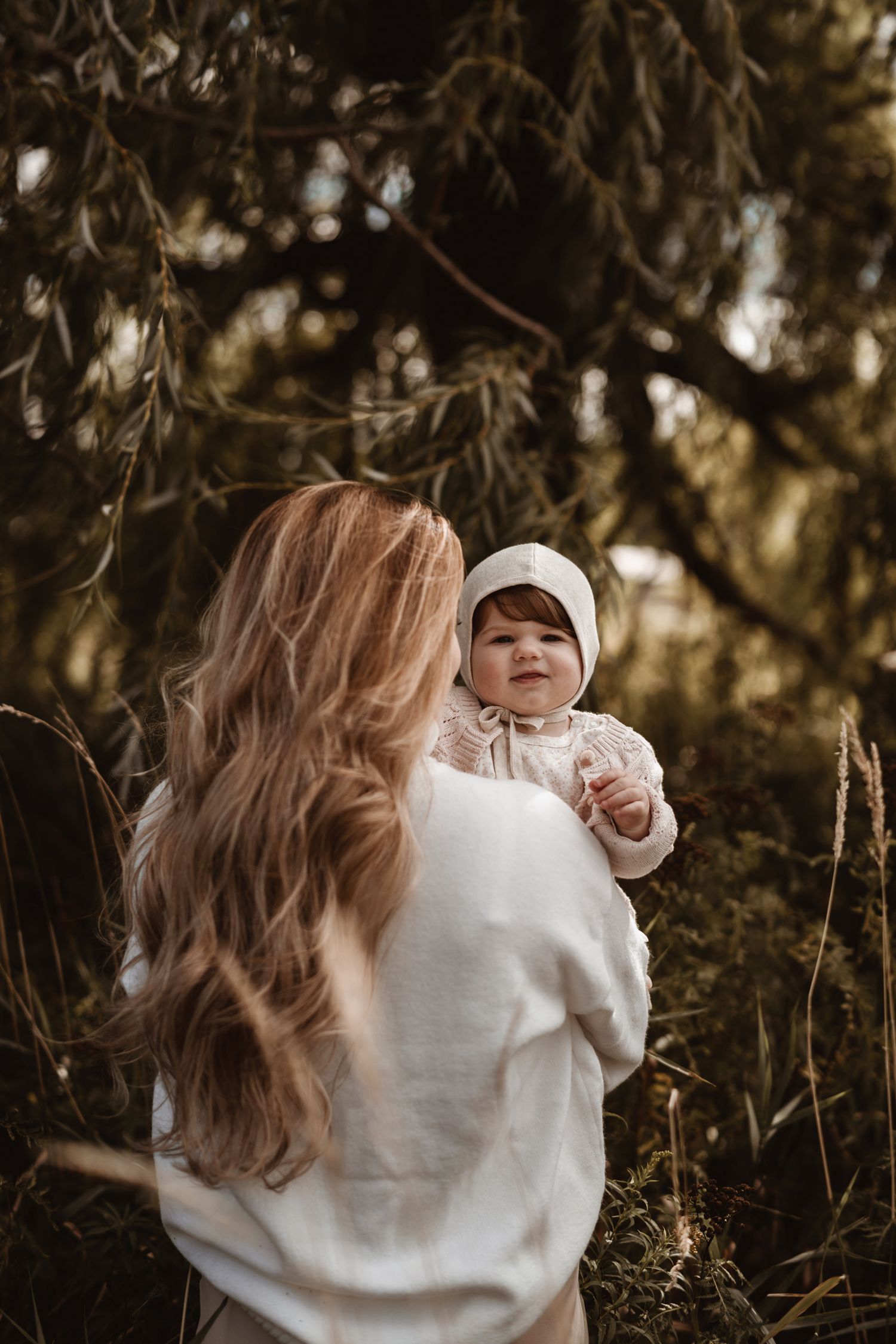 Tender family moment photographed under willow trees in golden light.