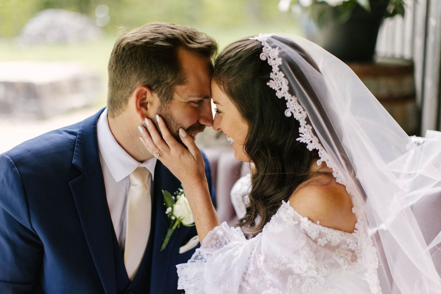 A tender wedding moment between newlyweds with lace veil details.