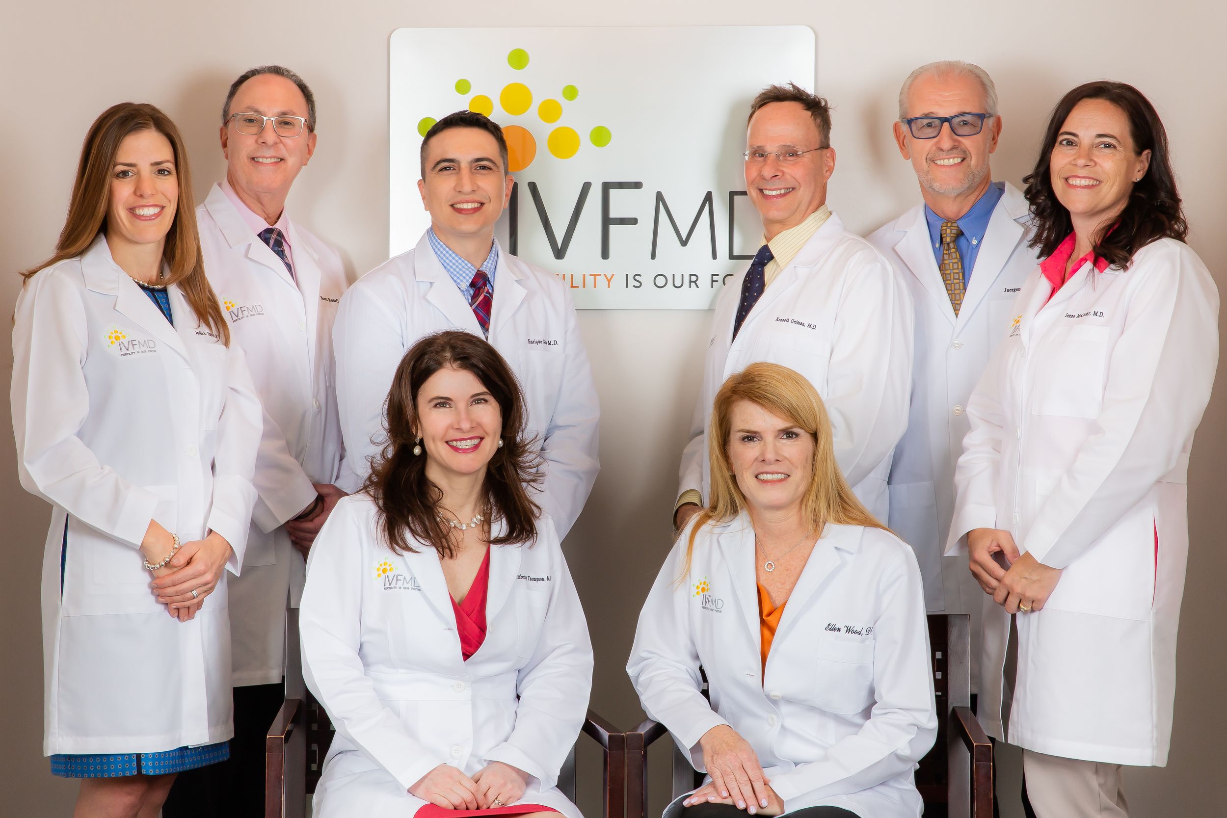 Group of medical professionals gather together in a bright office setting.