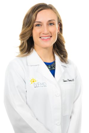 Healthcare professional in white coat smiling against white background.