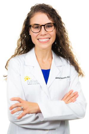 Medical professional in white coat posing confidently against white background.