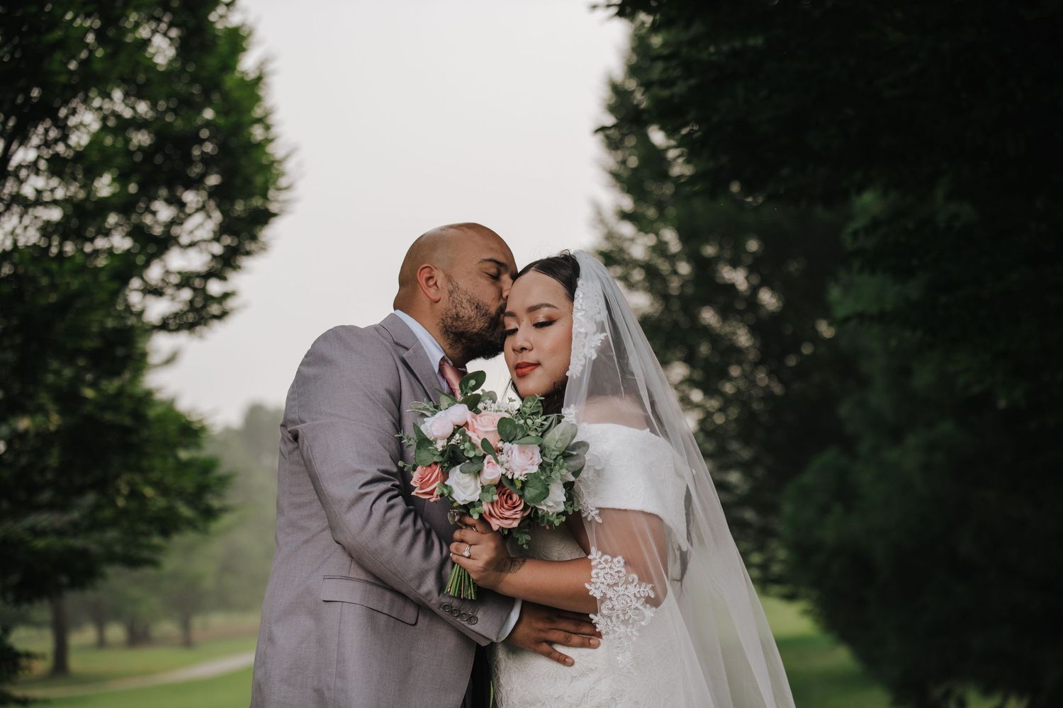 Intimate wedding moment captured in a lush garden setting with delicate floral bouquet.
