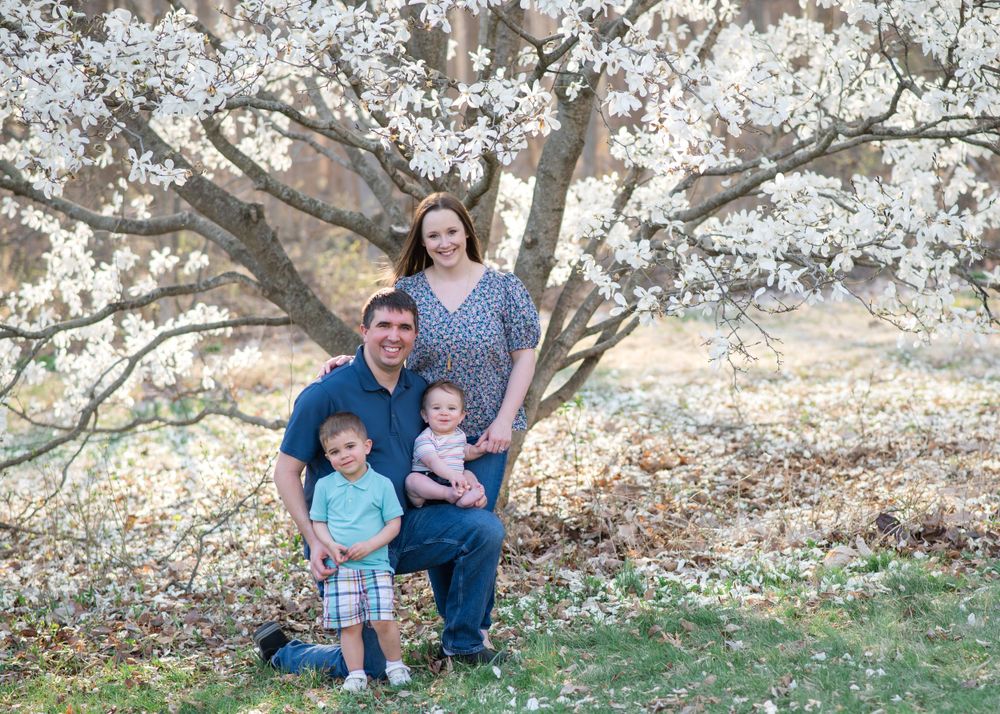 Family portrait under blooming spring cherry blossom tree.