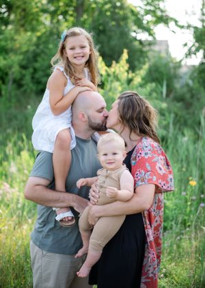Family embraces in outdoor garden setting during golden hour.