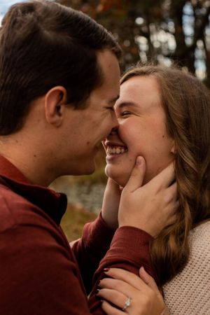 A close-up romantic moment between a couple wearing burgundy and beige sweaters in an autumn setting.