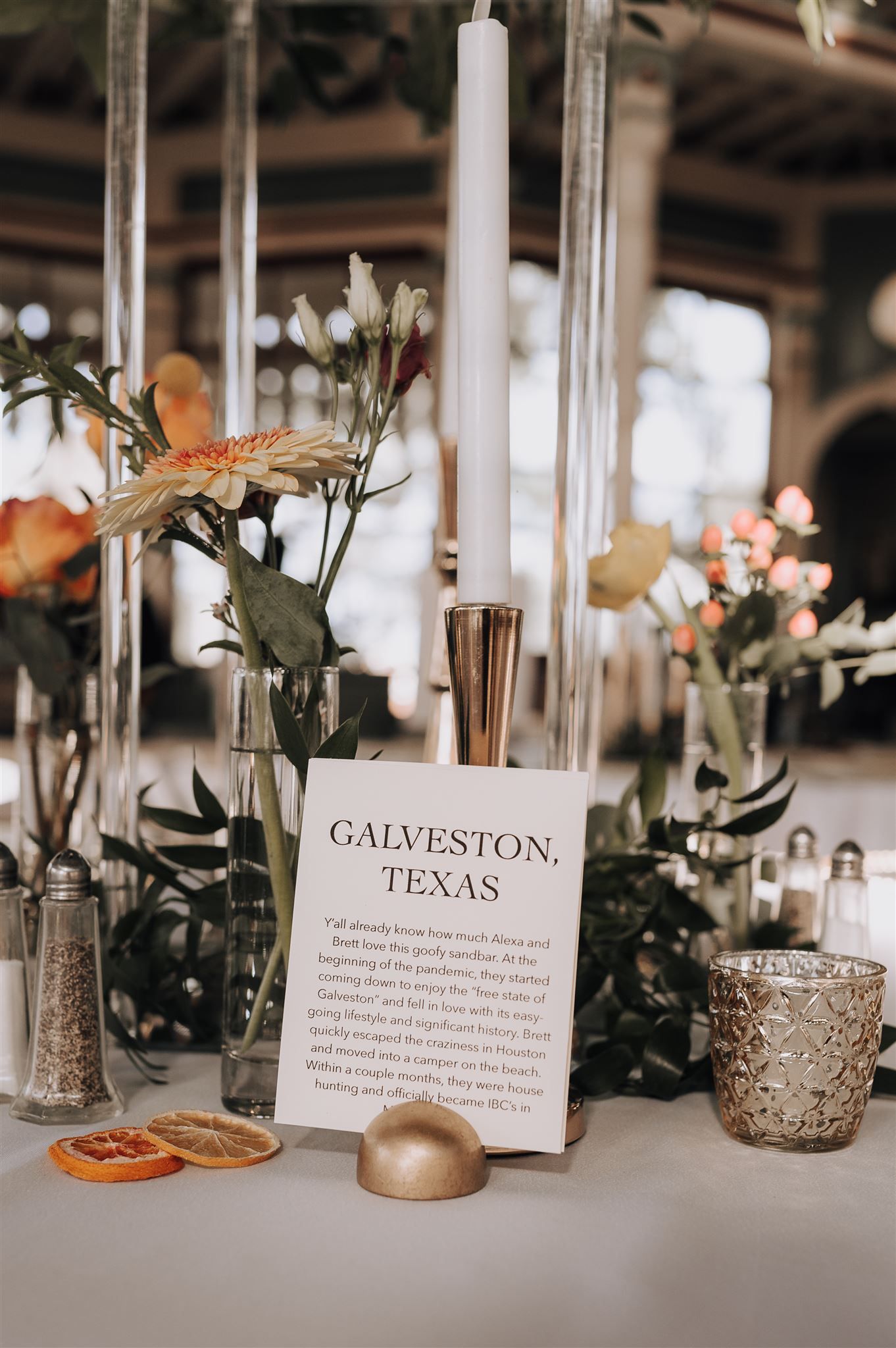 Wedding centerpiece with candles, flowers, and Galveston Texas information card.