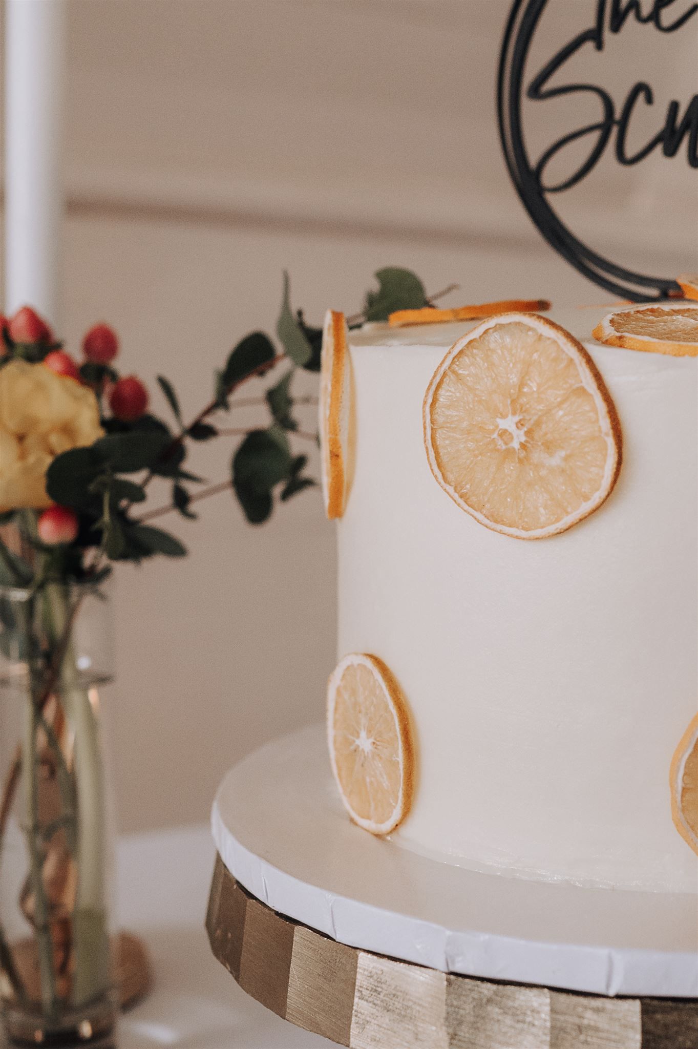 White wedding cake decorated with dried citrus slices and modern text topper.