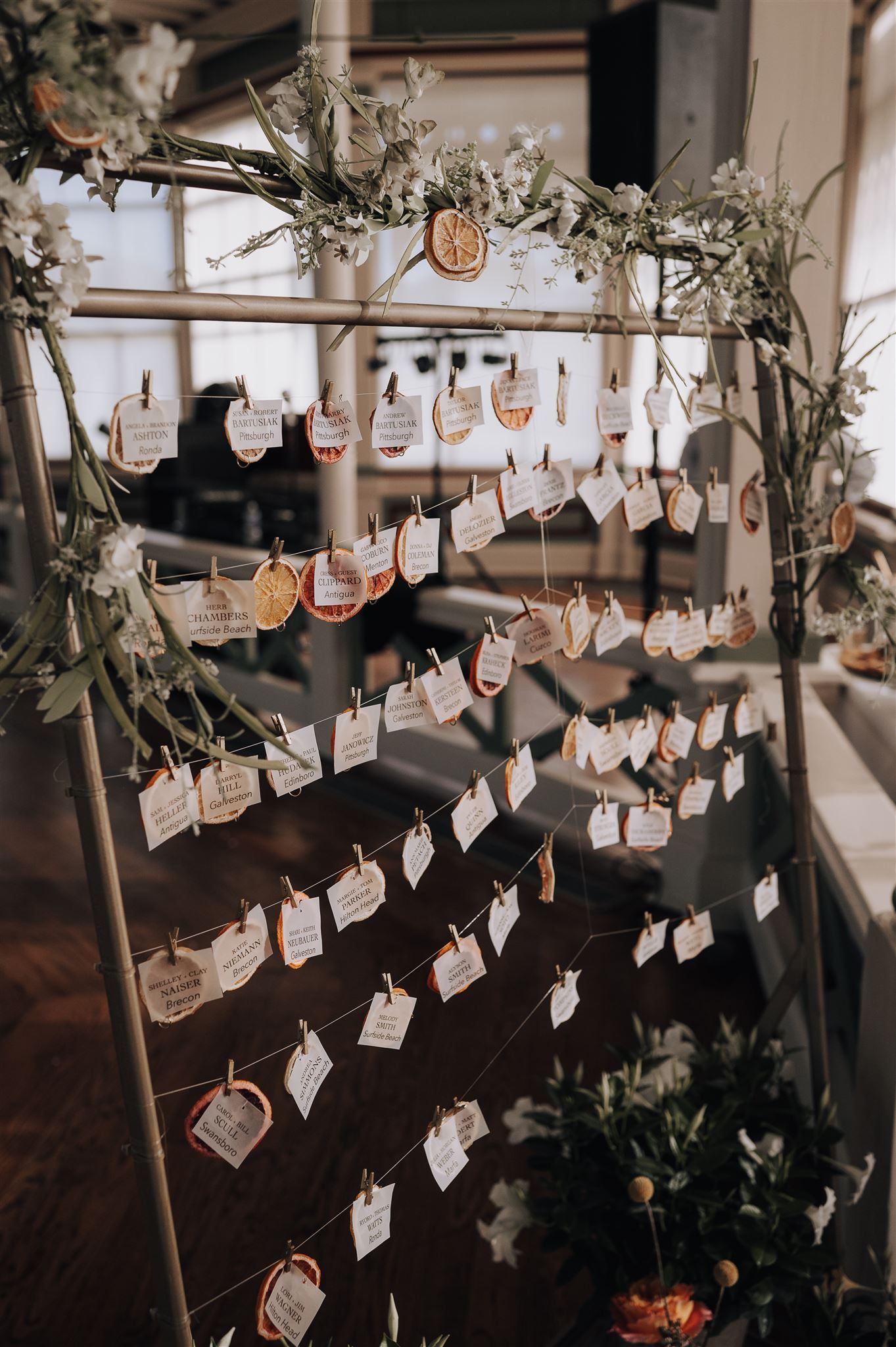 Rustic wedding seating chart display with cards hanging from floral-decorated strings.