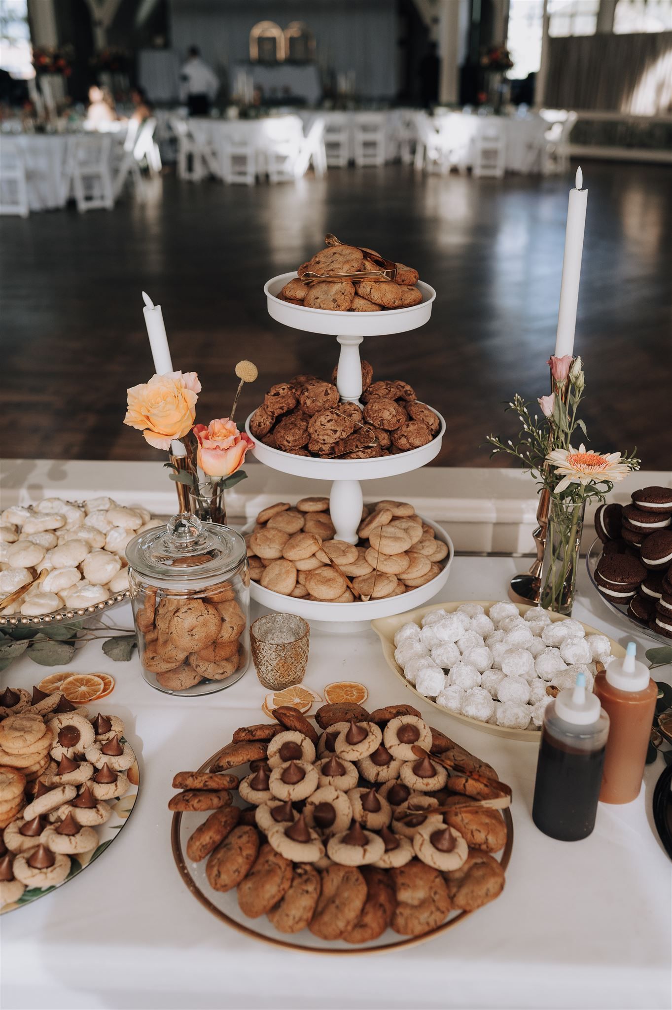 Elegant dessert table with tiered cookie displays, candlesticks, and floral arrangements.
