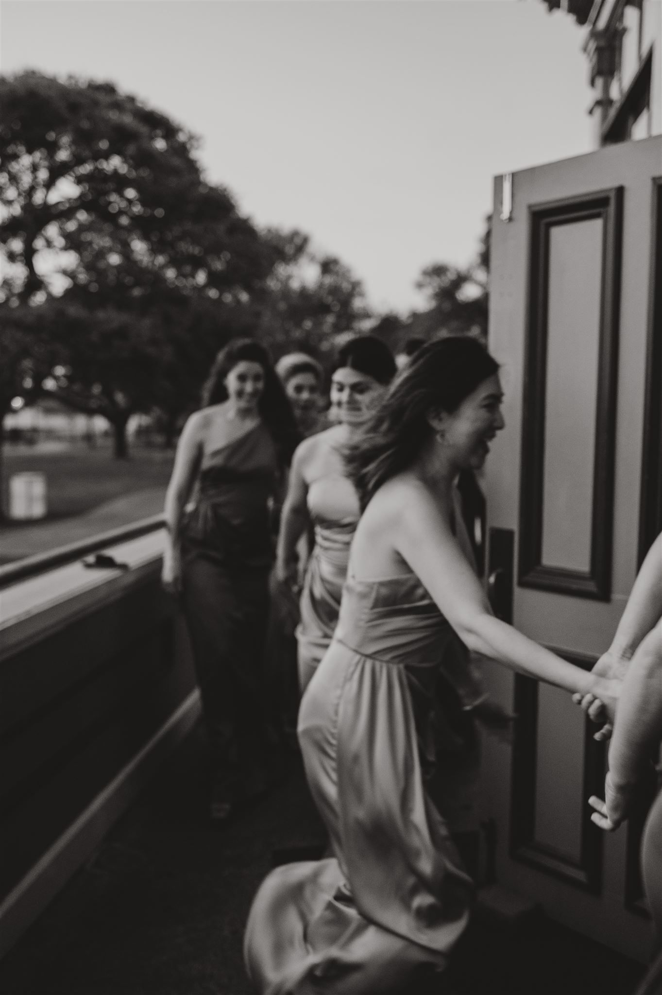 Black and white photo of bridesmaids in flowing dresses on vintage platform.