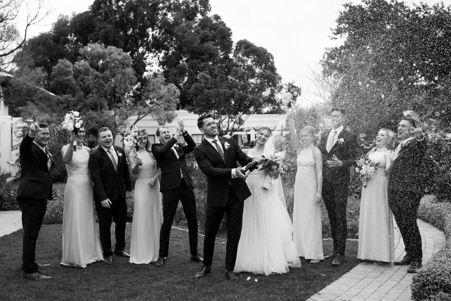 couple and their bridal party spraying champagne at Erinvale Estate