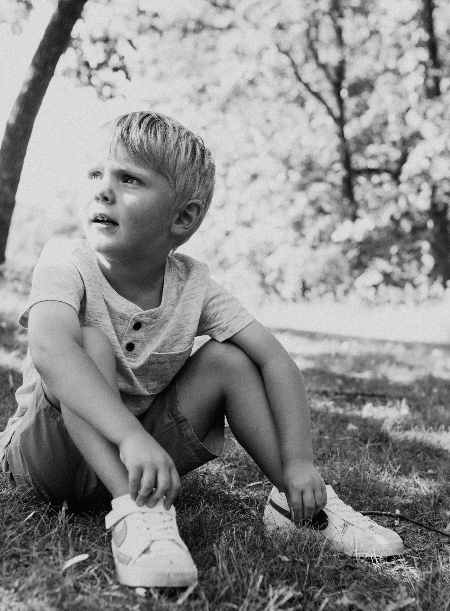 Black and white photos of toddler exploring and playing in grass outdoors.