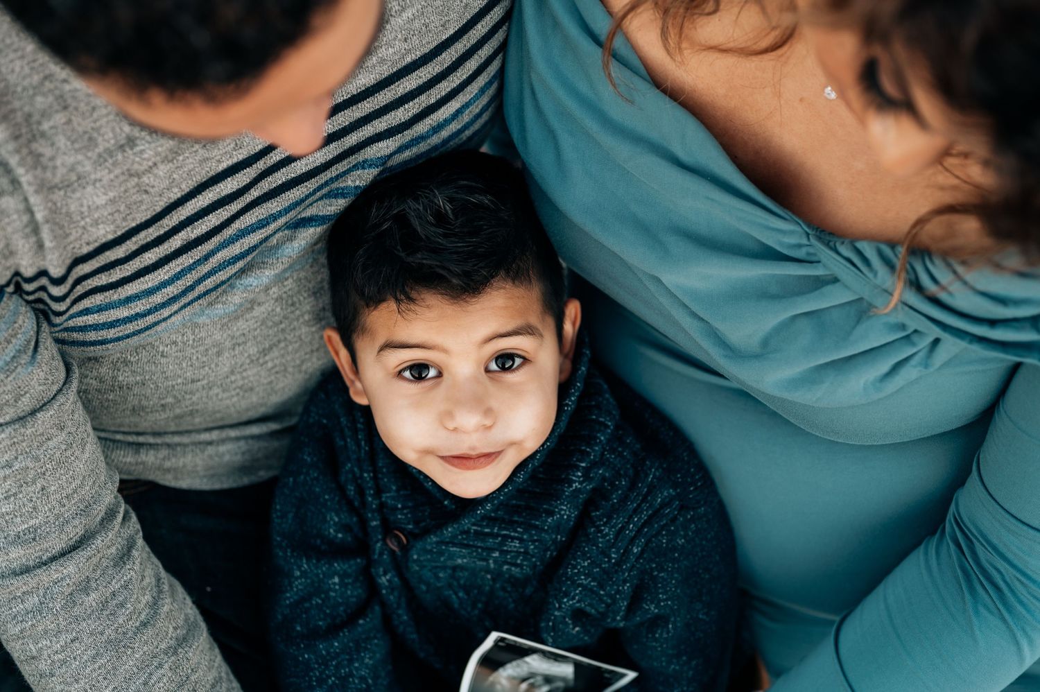 boy sitting in parents lap at maternity session holding sonogram at Murrell Park grapevine