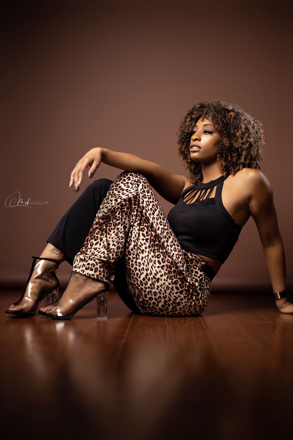 Stylish fashion portrait featuring leopard print pants and black top on wooden floor.