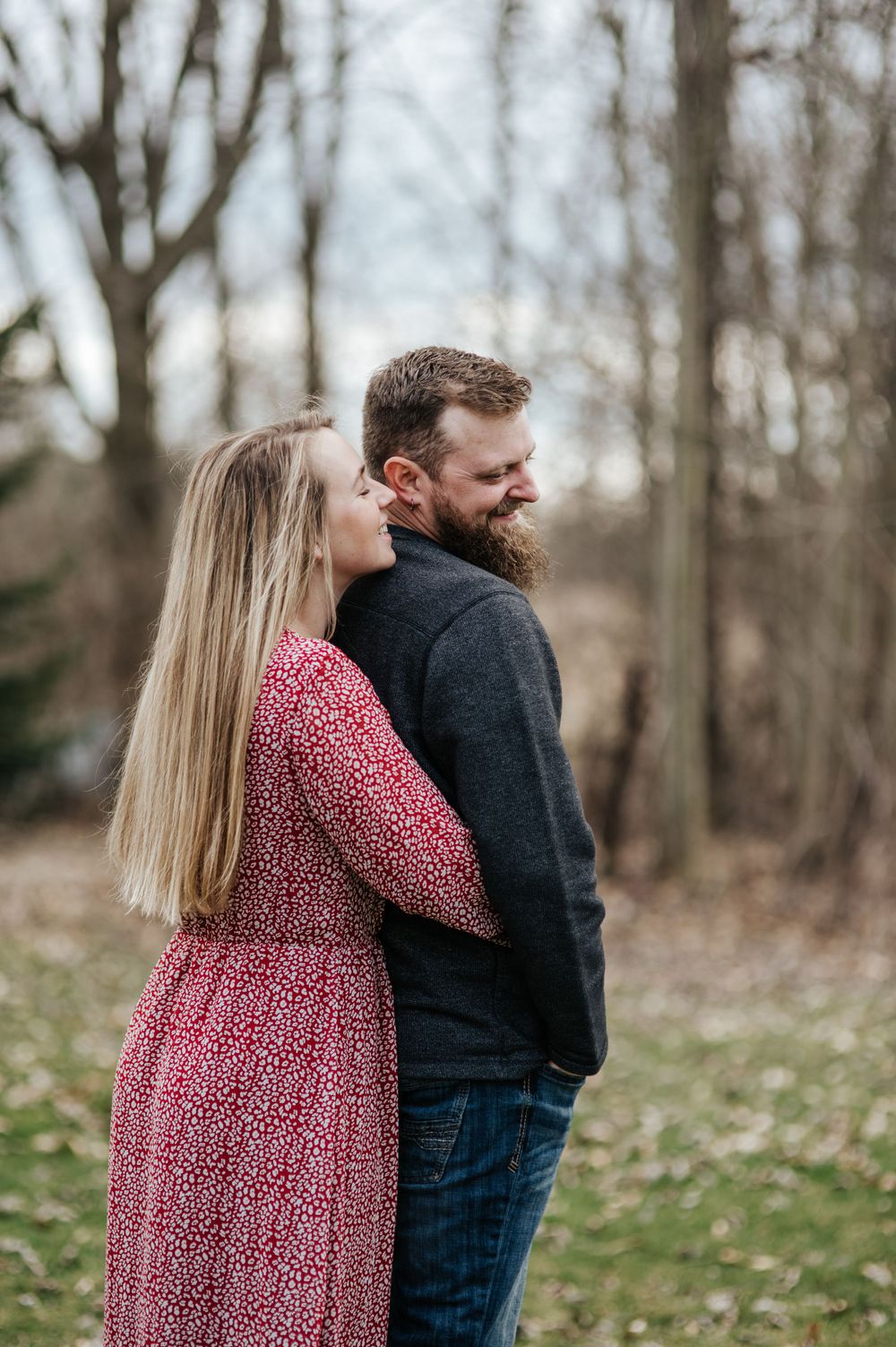 A tender outdoor portrait with person in pink dress embracing partner in dark sweater.