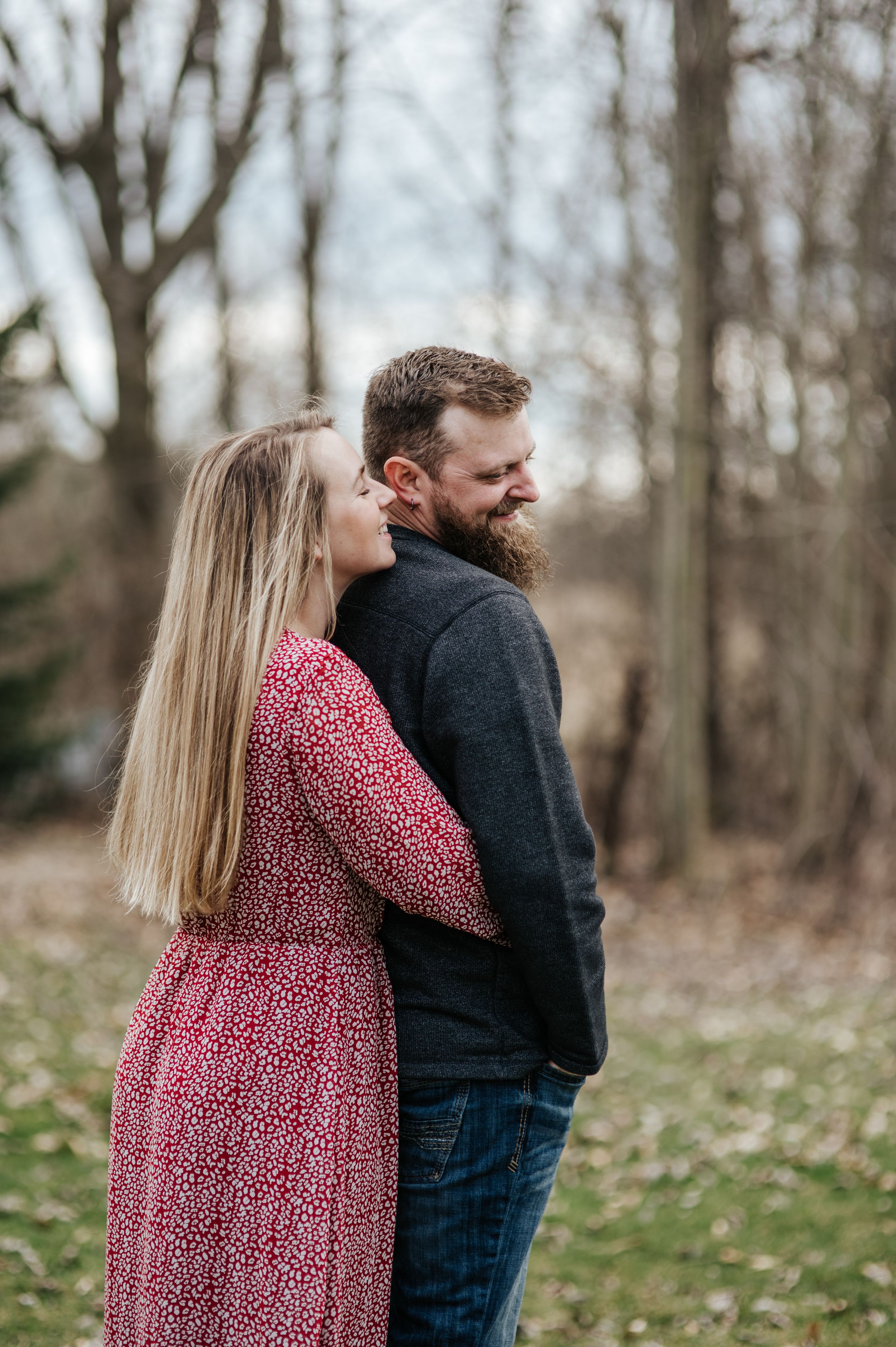 A tender outdoor portrait with person in pink dress embracing partner in dark sweater.