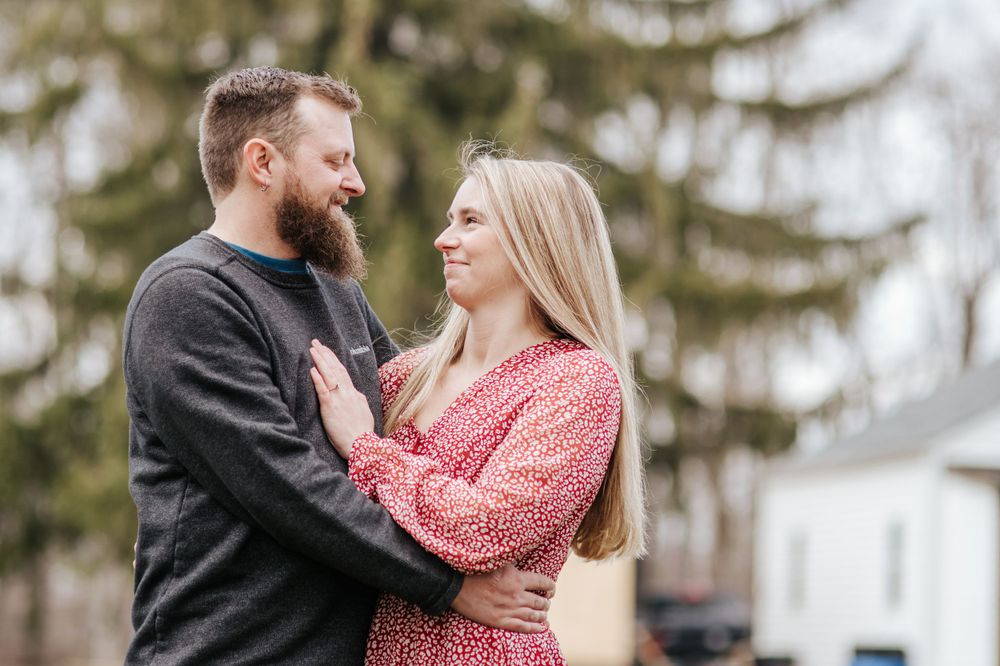 A joyful outdoor portrait with person in pink floral dress and partner in dark sweater.