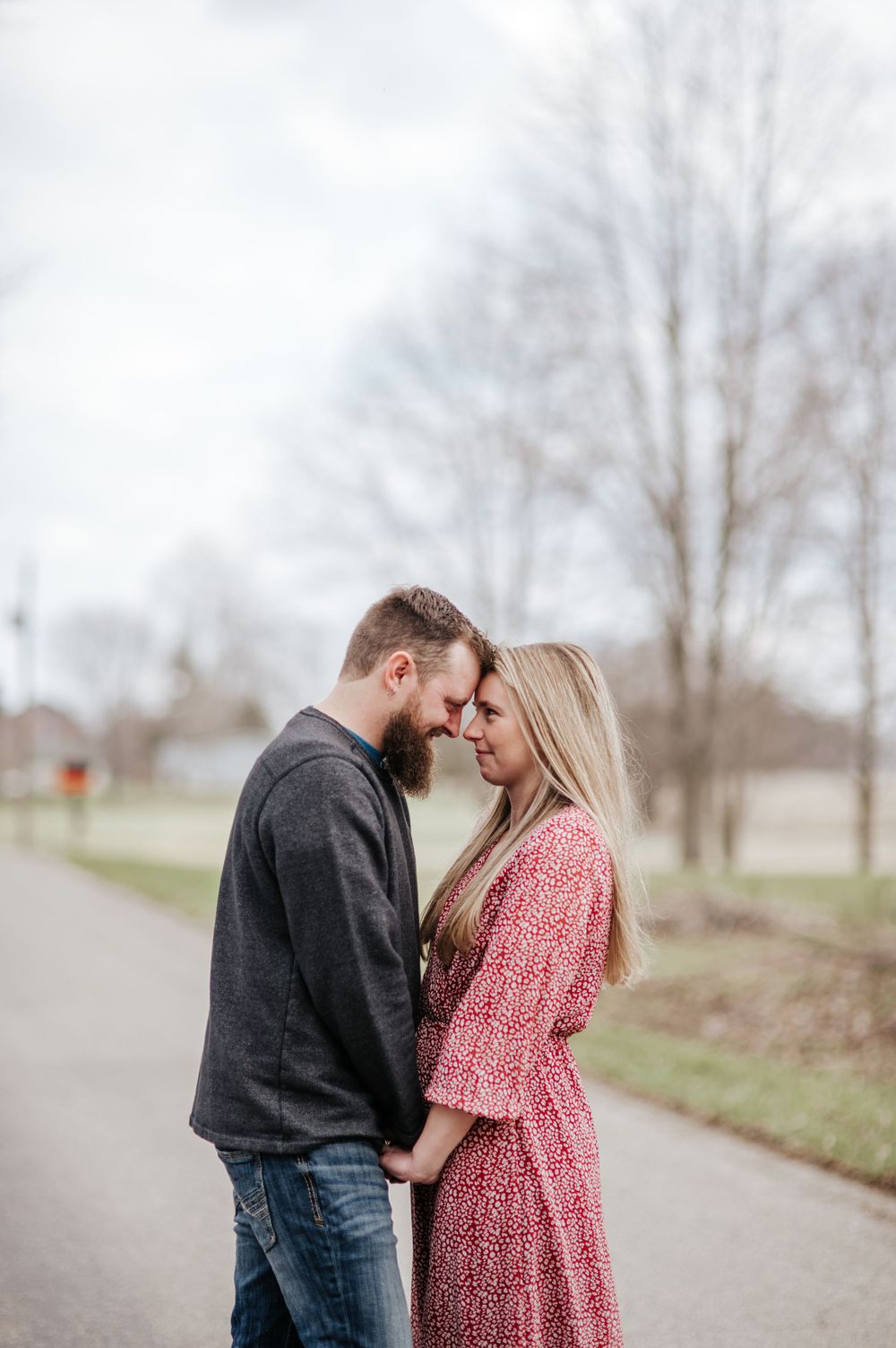 Couple shares tender moment during engagement photoshoot on path.