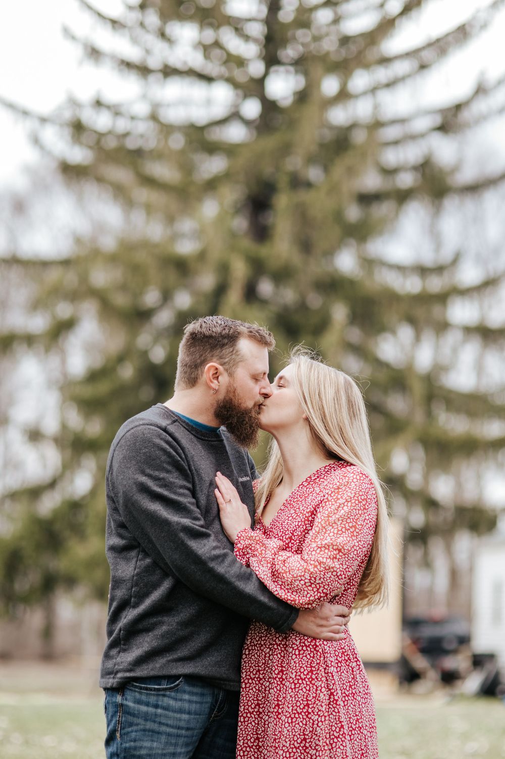 Romantic outdoor engagement photos with evergreen trees in background.