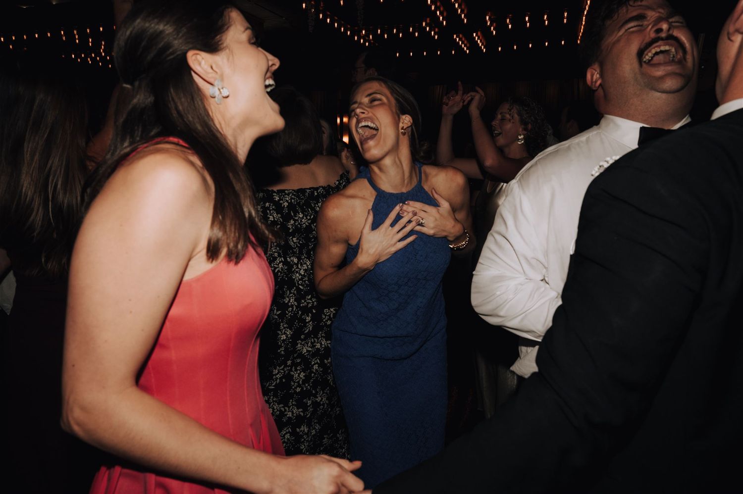 Lively dance floor scene with guests singing and dancing at a formal celebration.