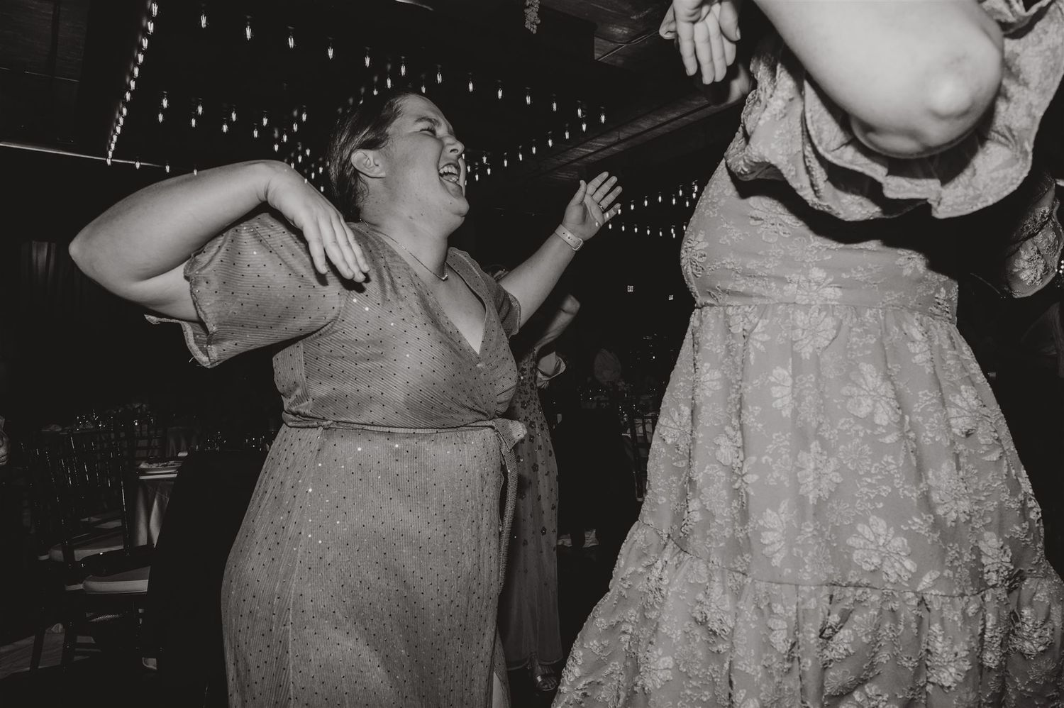 Black and white photo of guests dancing energetically at a wedding reception.