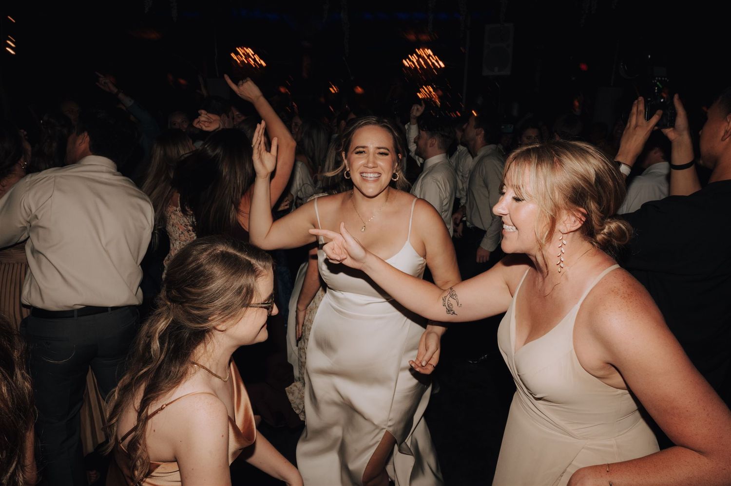 Wedding guests dancing and celebrating with joyful expressions on the dance floor.