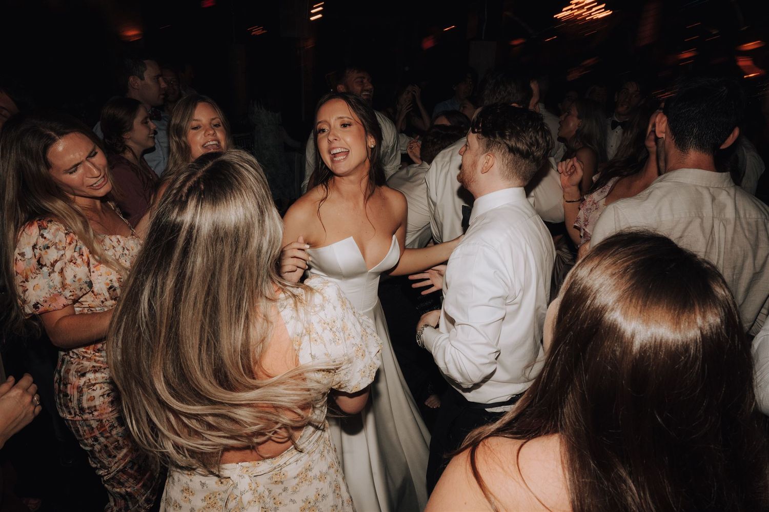 Wedding reception dance floor filled with guests celebrating in formal attire.
