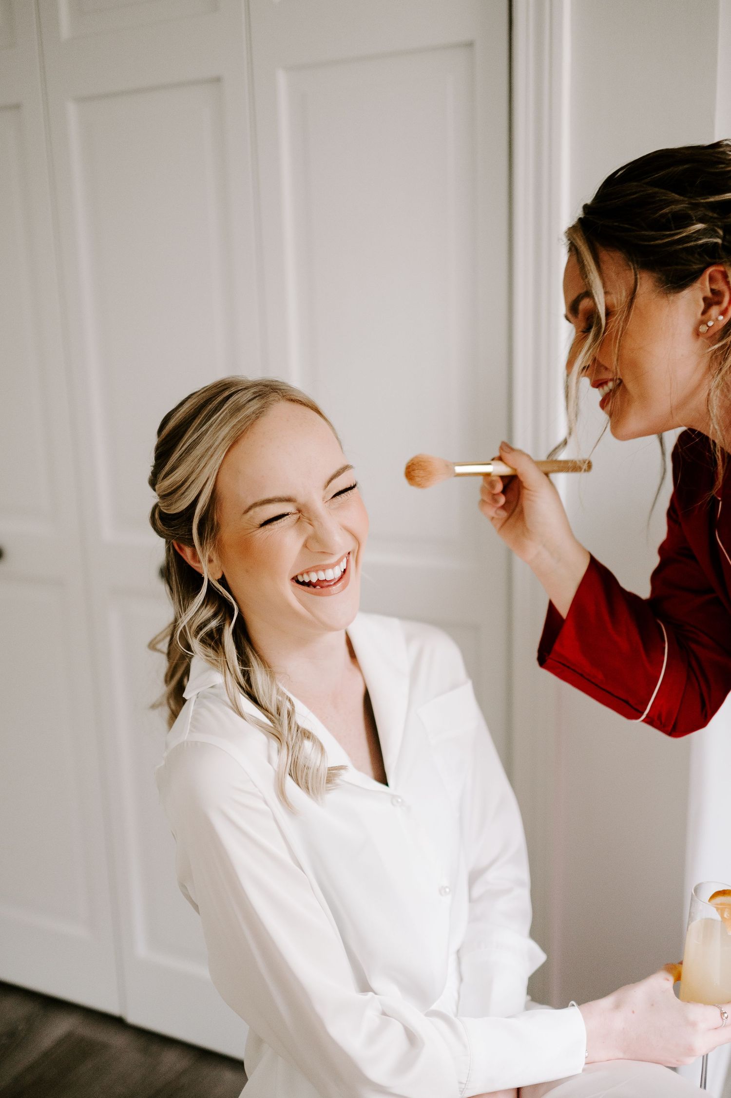 Joyful candid moments captured during wedding day preparations in white room.
