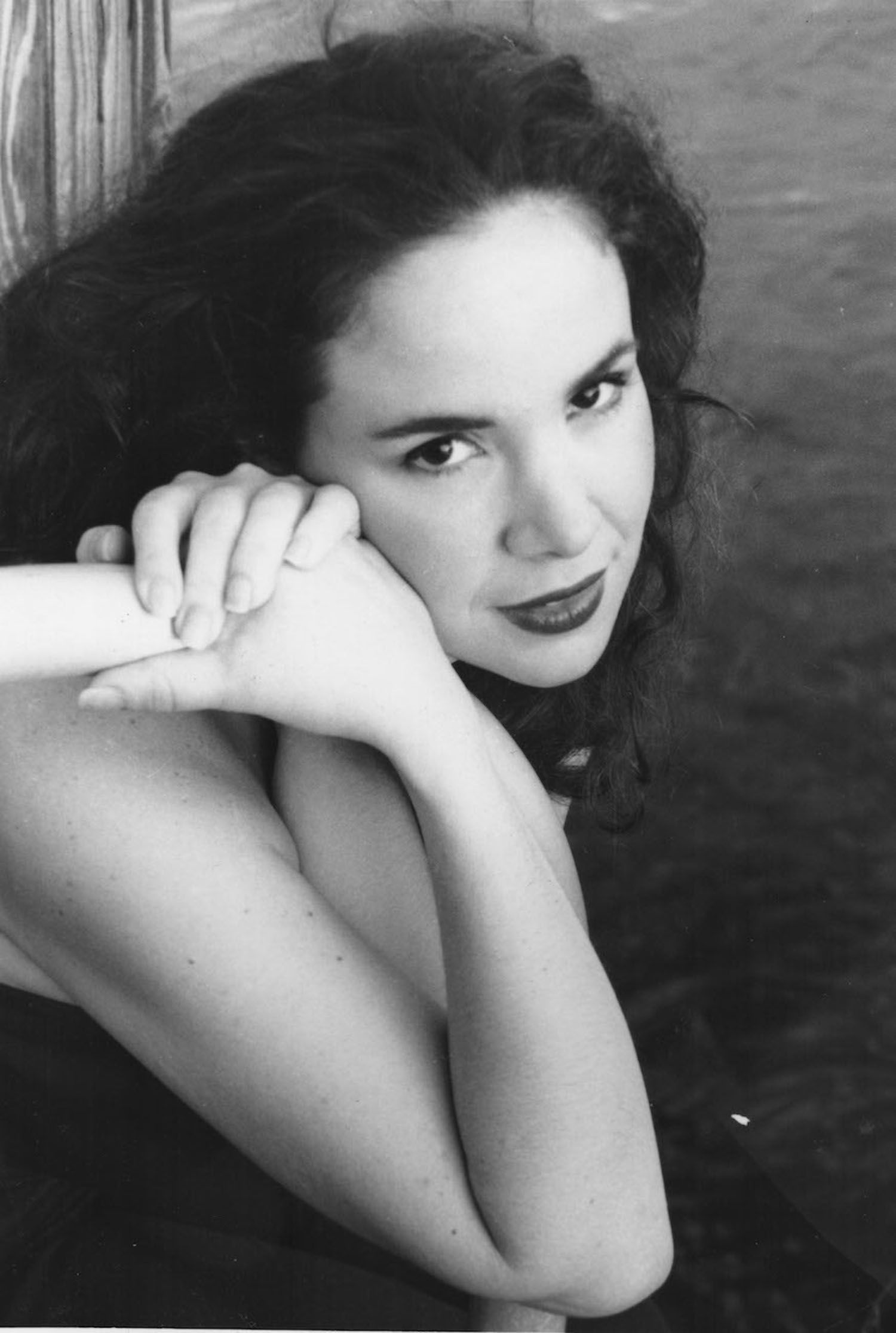 a black and white photo of a woman leaning against a wood wall
