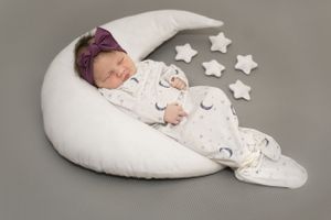 Baby sleeping on crescent moon pillow with decorative stars.
